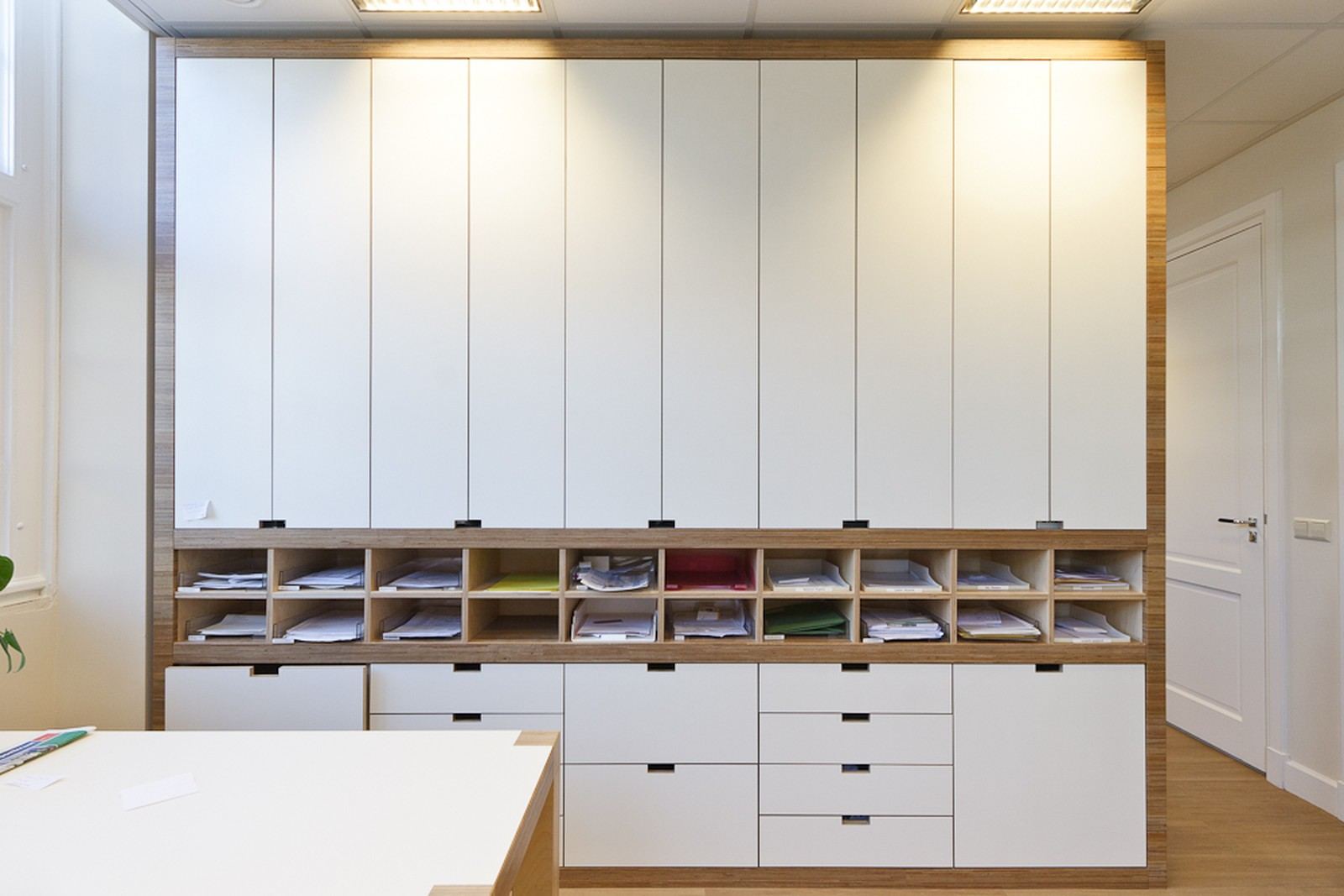 Wandvullende kastenwand met witte deuren en een rij postvakjes.