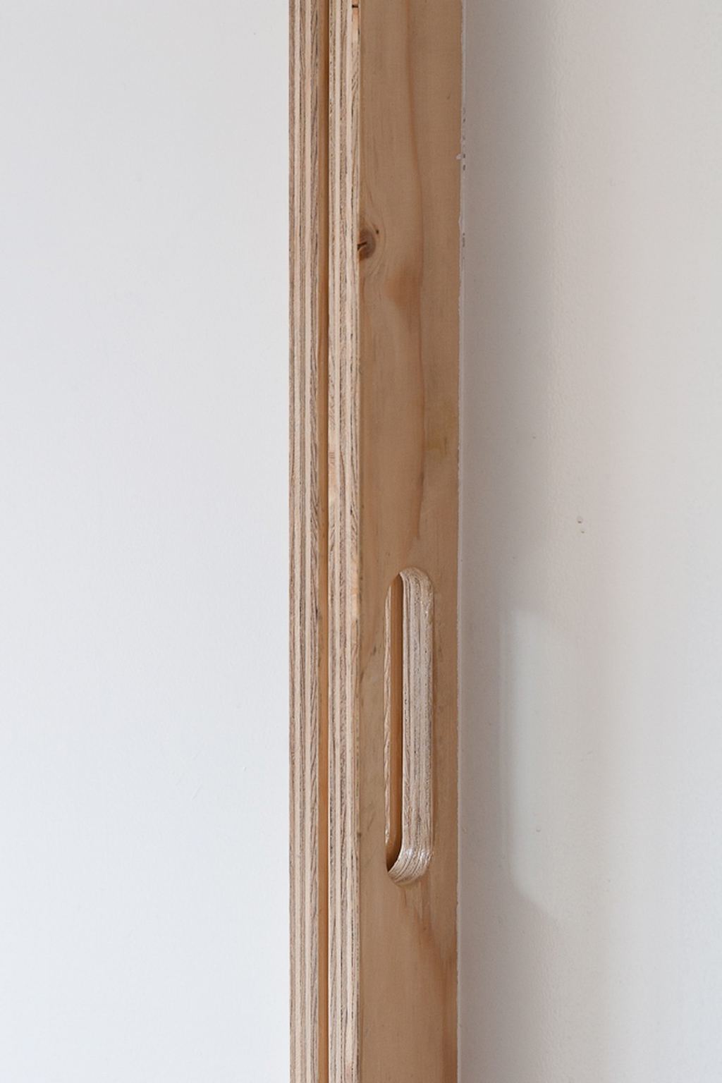 Detail van de verticale greepgroef in een vuren kastdeur.