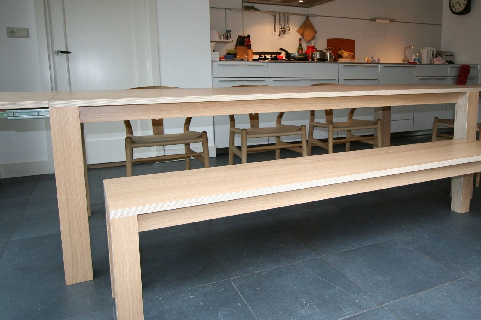 Lange eettafel van gestreept hout, met een bijpassende bank aan de zijkant.