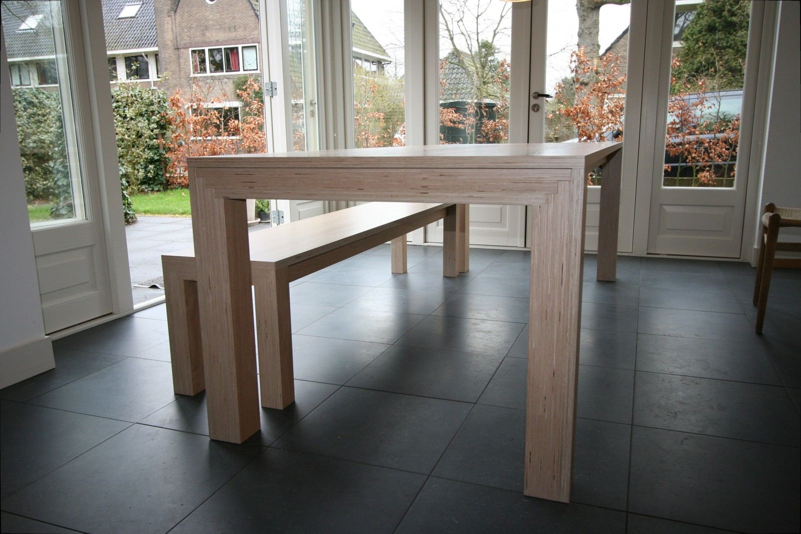 Eettafel van gestreept hout, met een bijpassende bank ernaast.