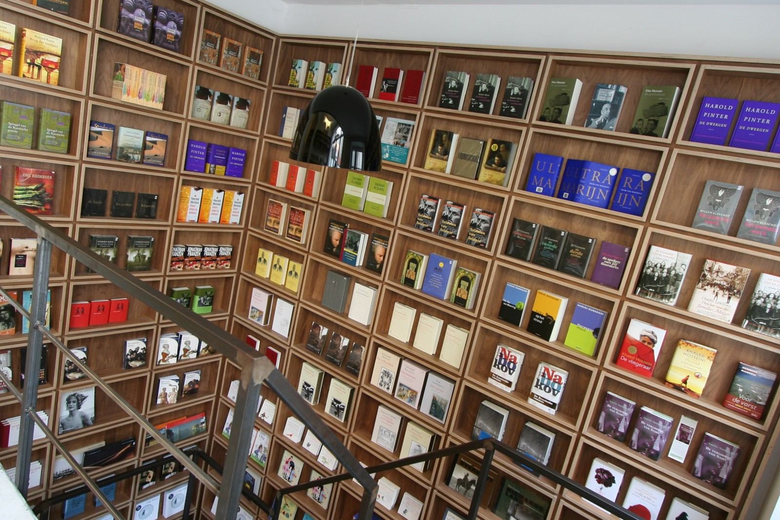 Berken multiplex boekenkast direct naast een stalen trap.