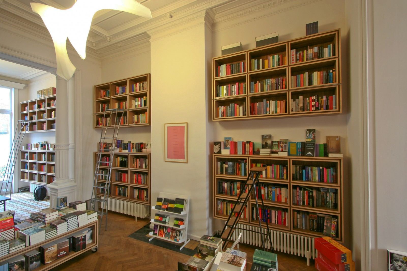 Notenfineer boekenkasten met rolladders in de klassieke voorwinkel.