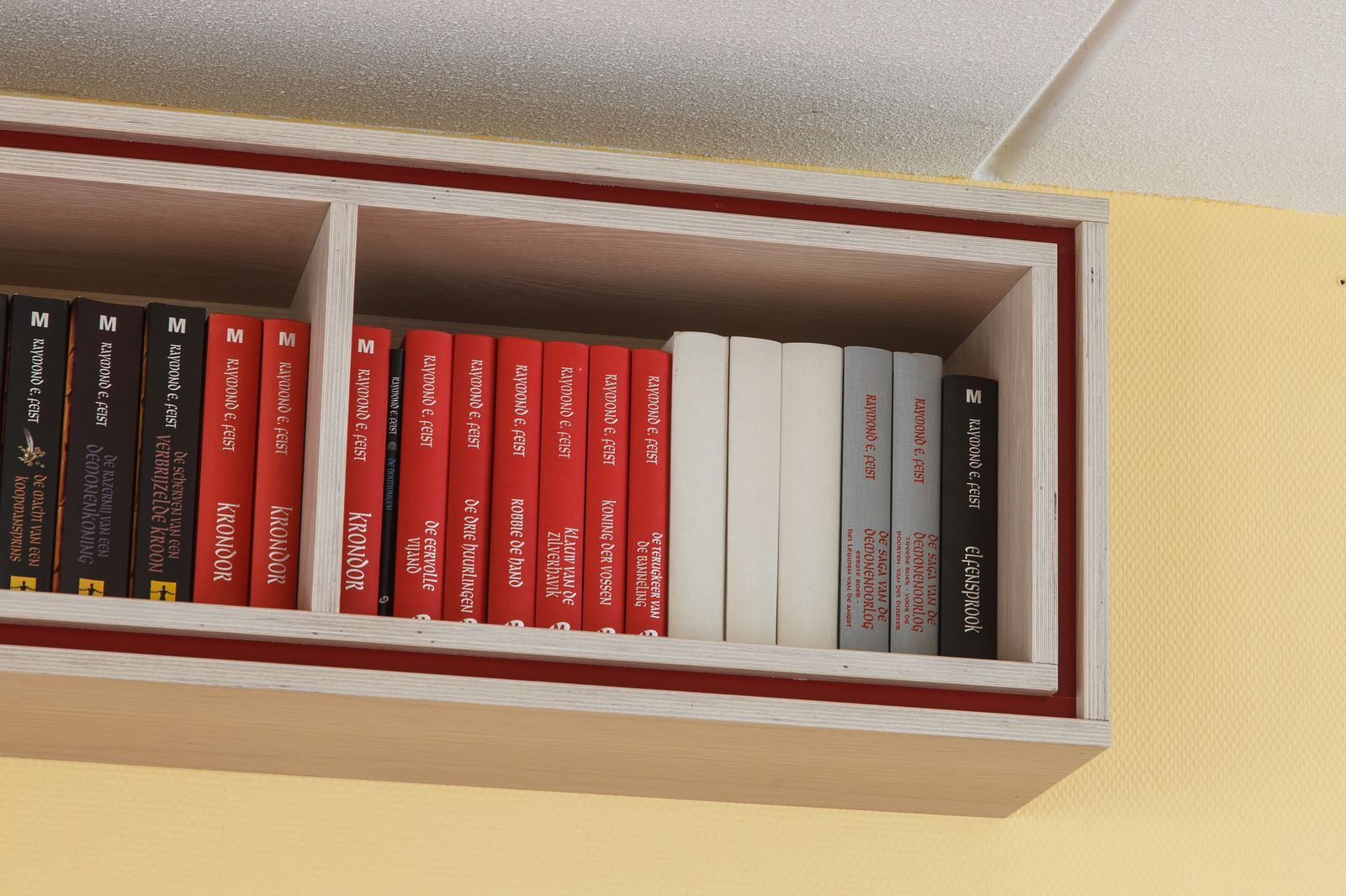 Detail van een vak in de wandkast, afgewerkt met een rode rand.