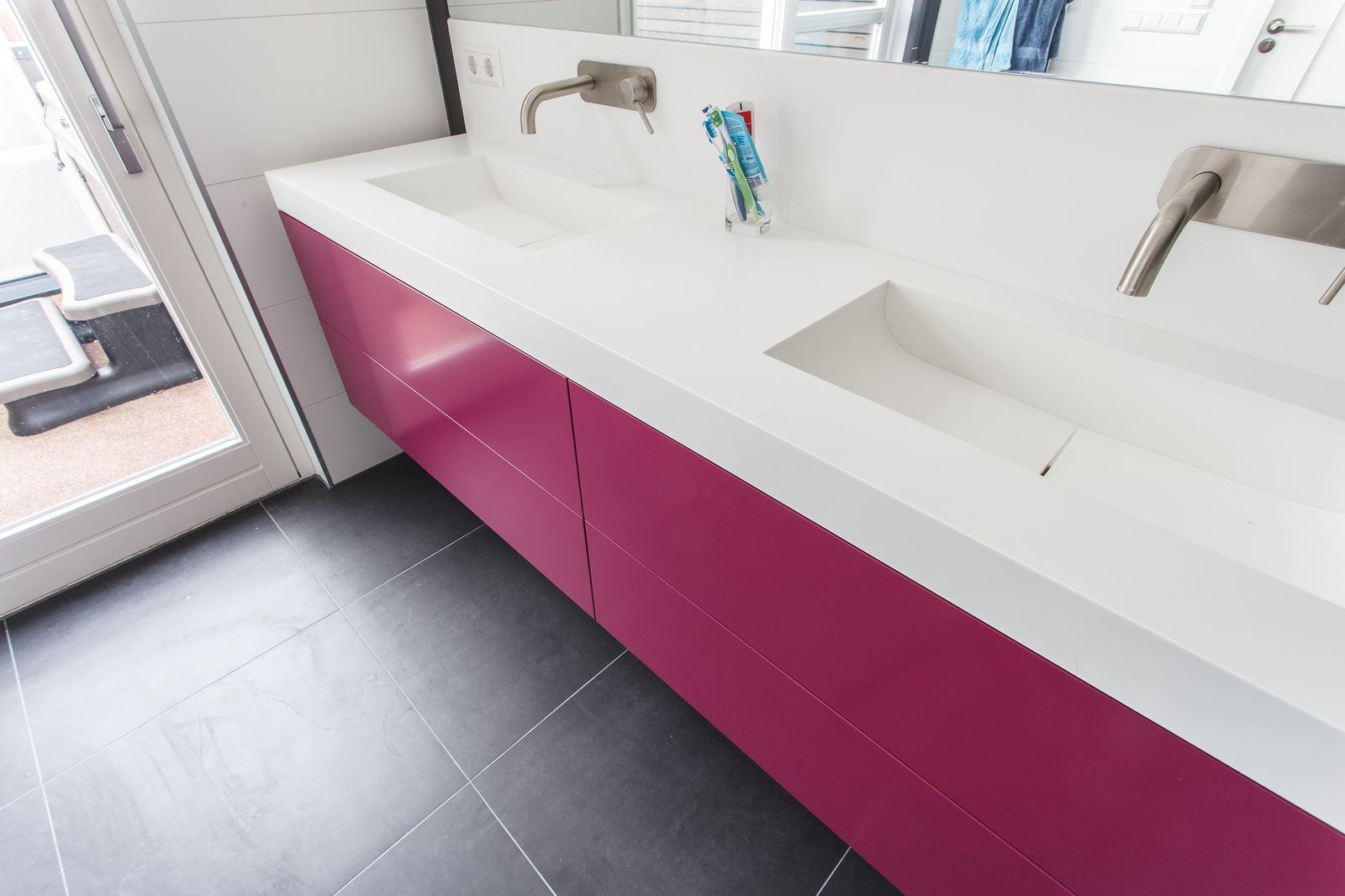 Zwevend badkamermeubel in magenta met twee wastafels naast elkaar in het witte blad.