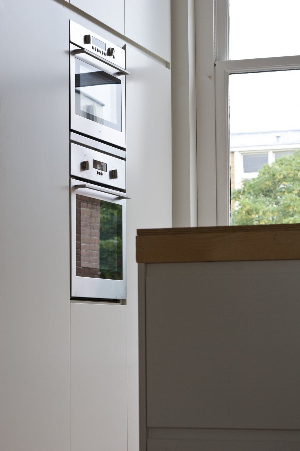 Ingebouwde dubbele oven tussen witte kastdeuren van de keuken.