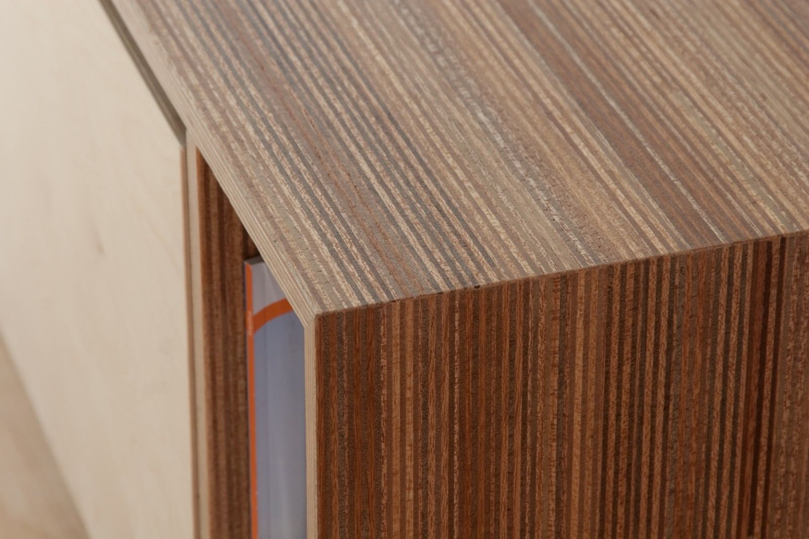 Detail van de hoek van een gestreept houten kastje, naast een open vak met een tijdschrift.
