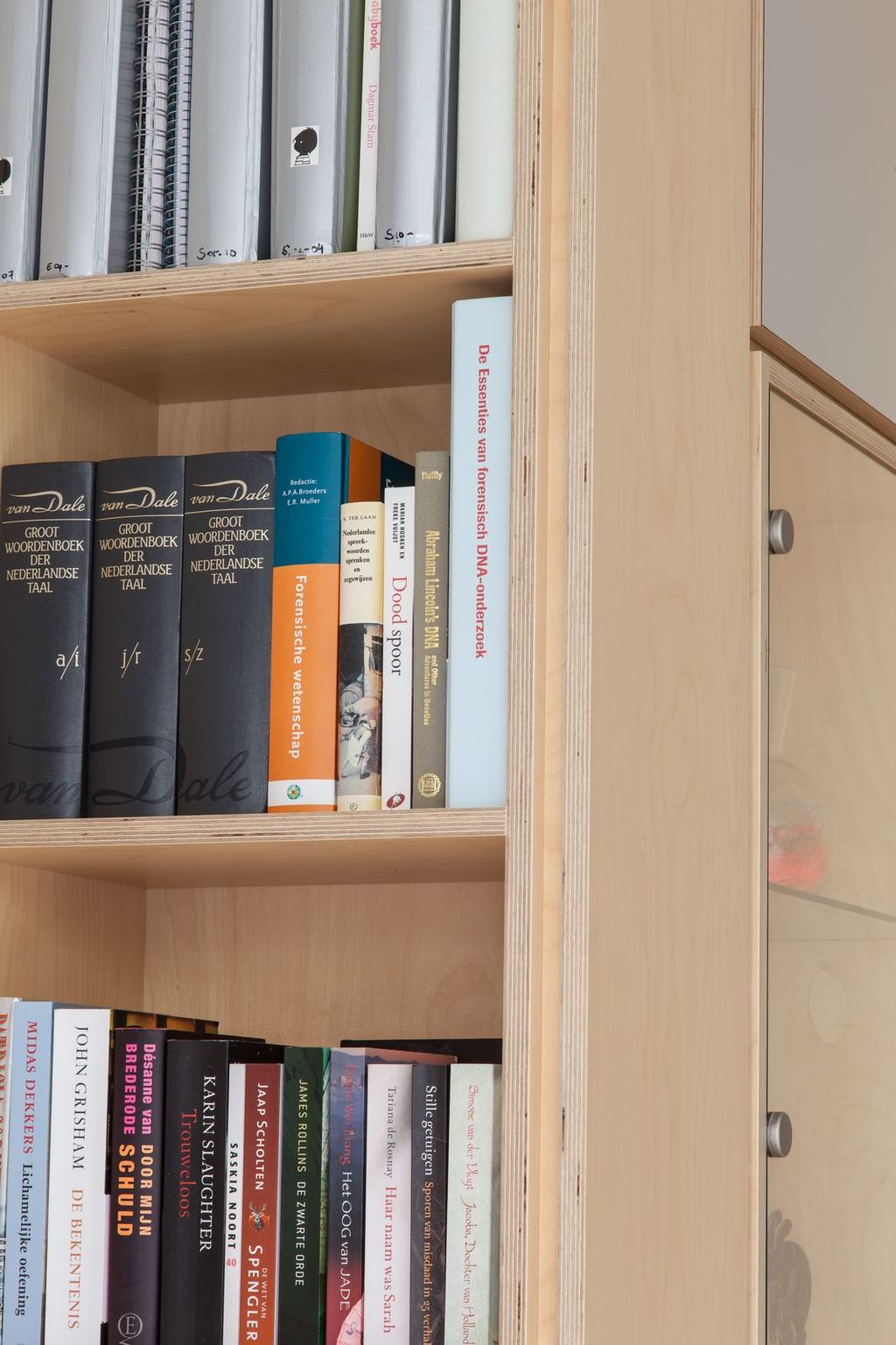 Boekenplank met naslagwerken tussen berken kastwanden.