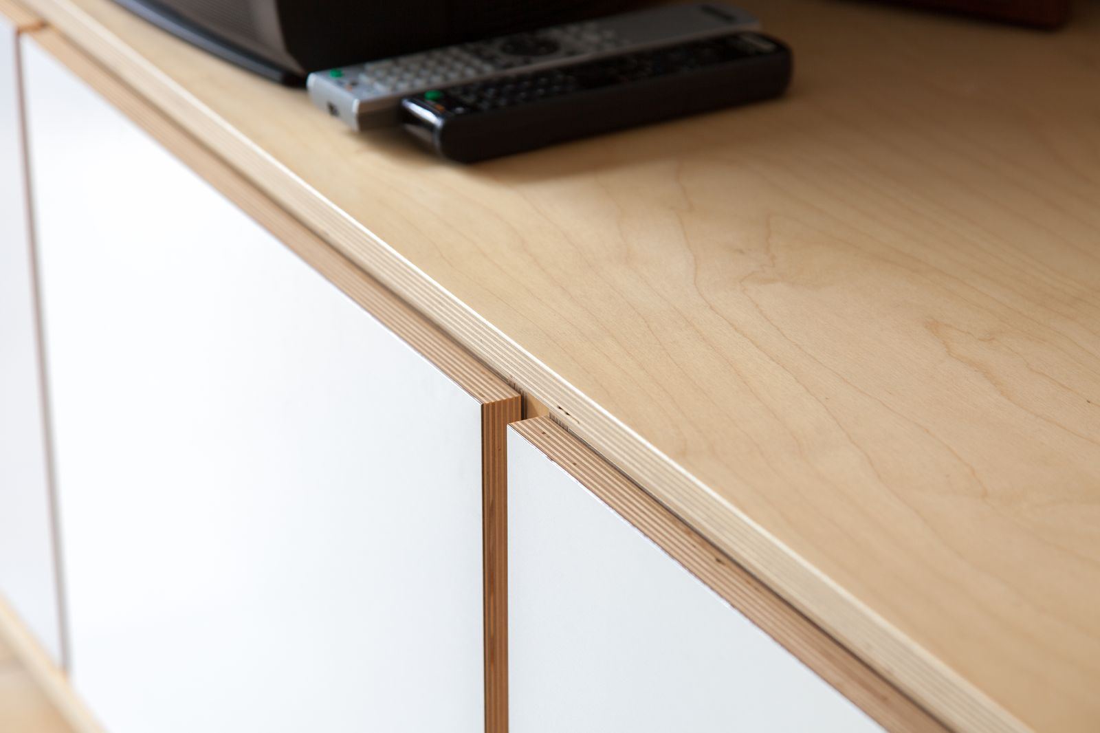Detail van de houten hoekafwerking van het dressoir met witte deuren.