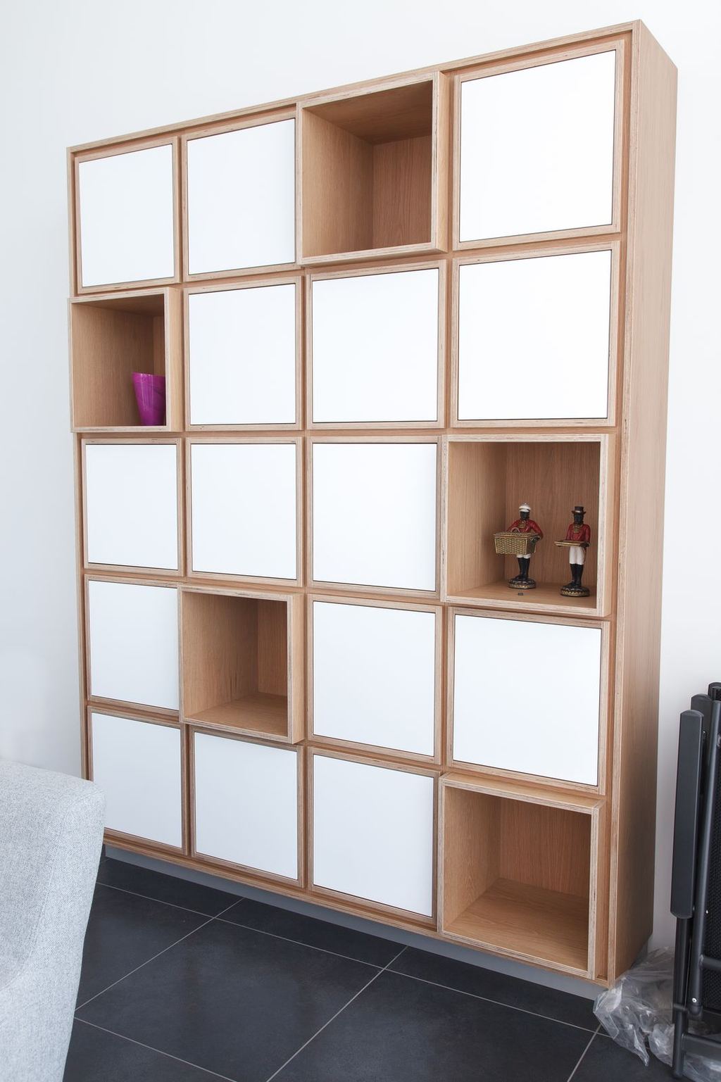 Wandvullende boekenkast met een raster van witte en open eiken vakken.