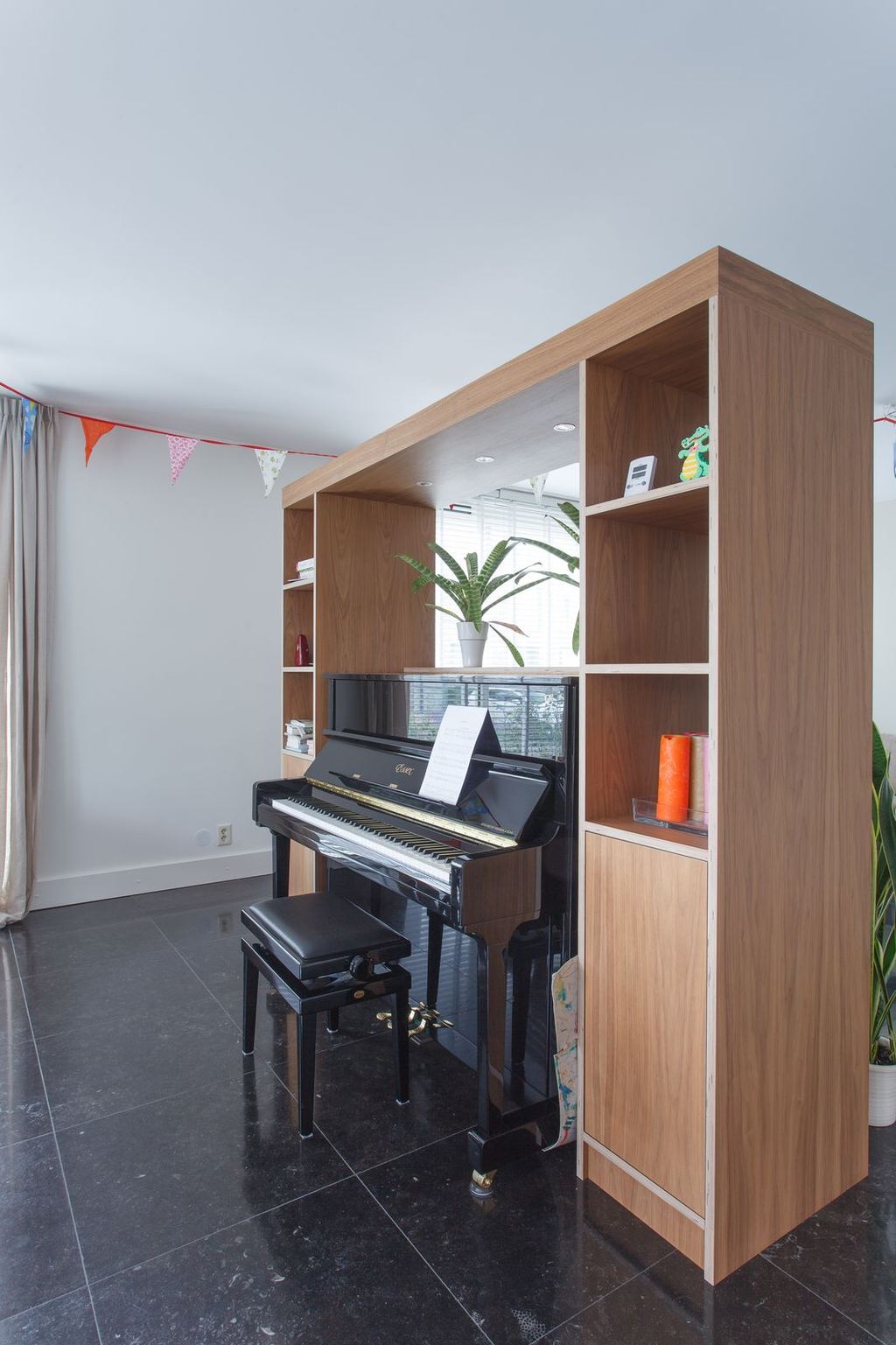 Kast met open vakken en een gesloten kastdeur naast een piano.