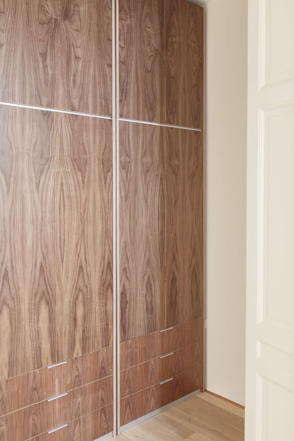 Hoge garderobekast in notenfineer met verticale aluminium strips.