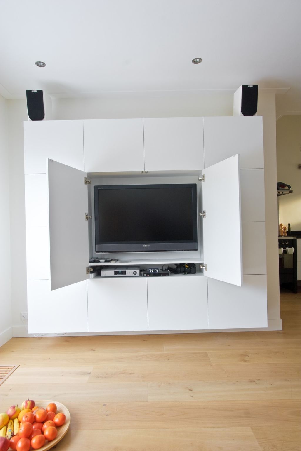 Witte kast met een verborgen televisie achter geopende deuren.