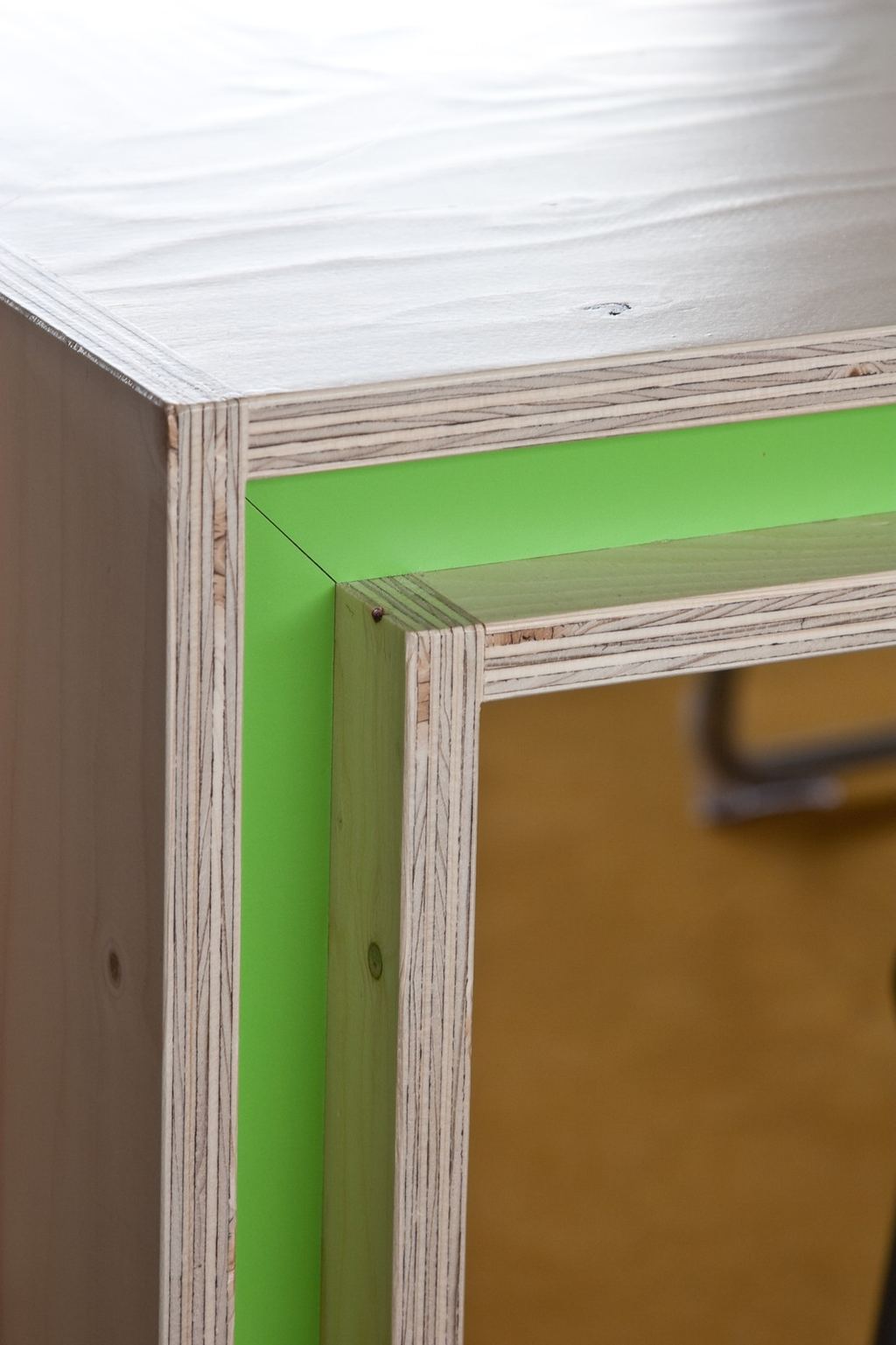 Detail van een wit gelakte kasthoek naast een groen HPL vlak.