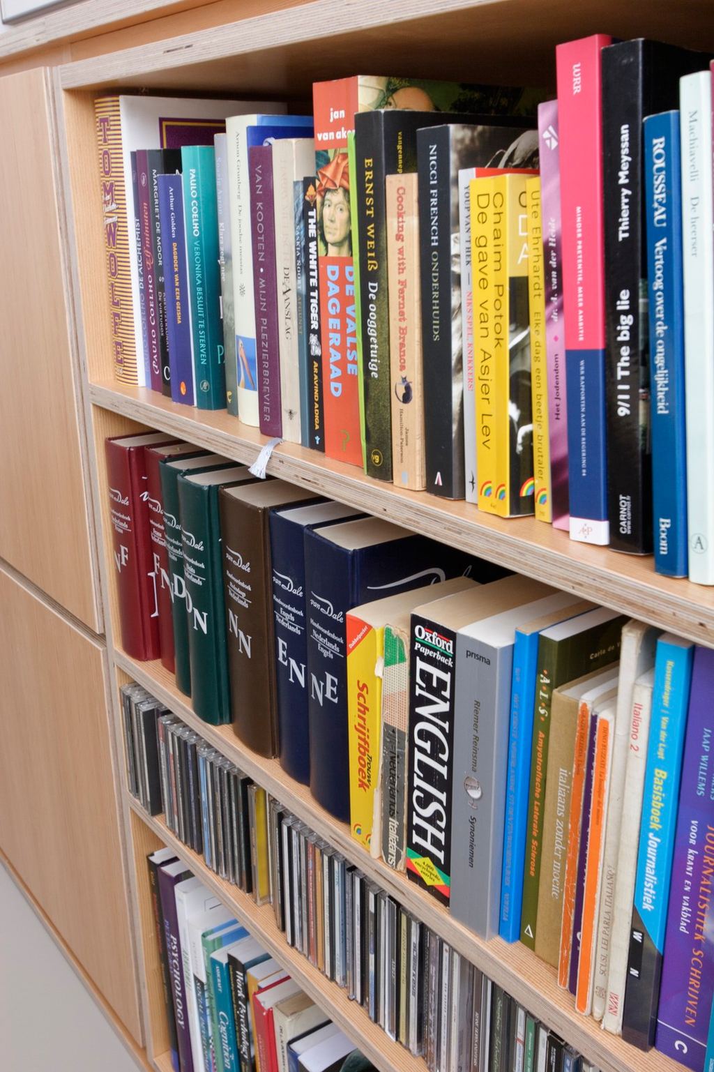 Schuin gefotografeerd vak met boeken en cd's in de boekenkast.