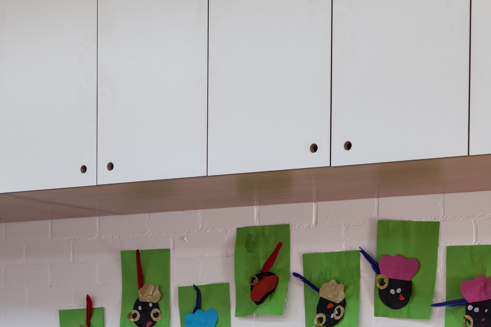 Detail van wandkastdeuren in wit HPL met ronde greepgaten.