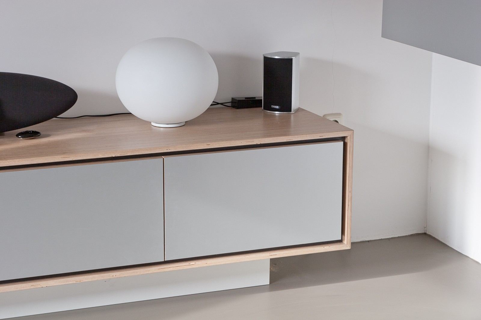 Hoek van het zwevend dressoir met een bollamp erop.