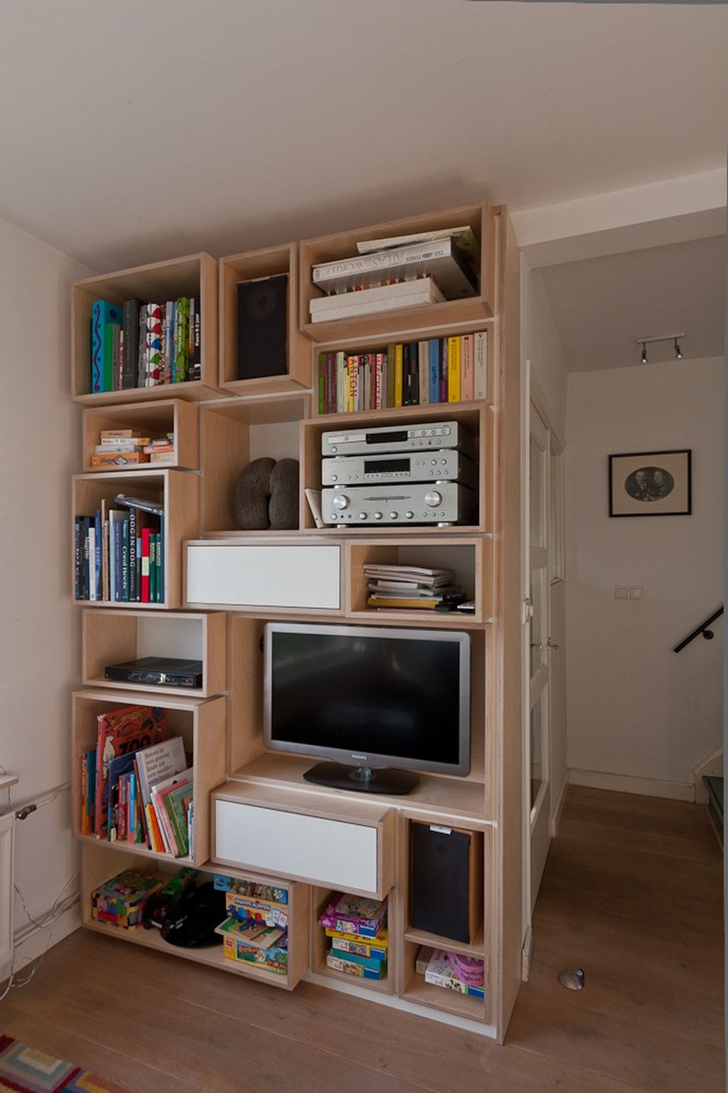 Bergkast van berken multiplex met een raster van open en gesloten vakken, met televisie.