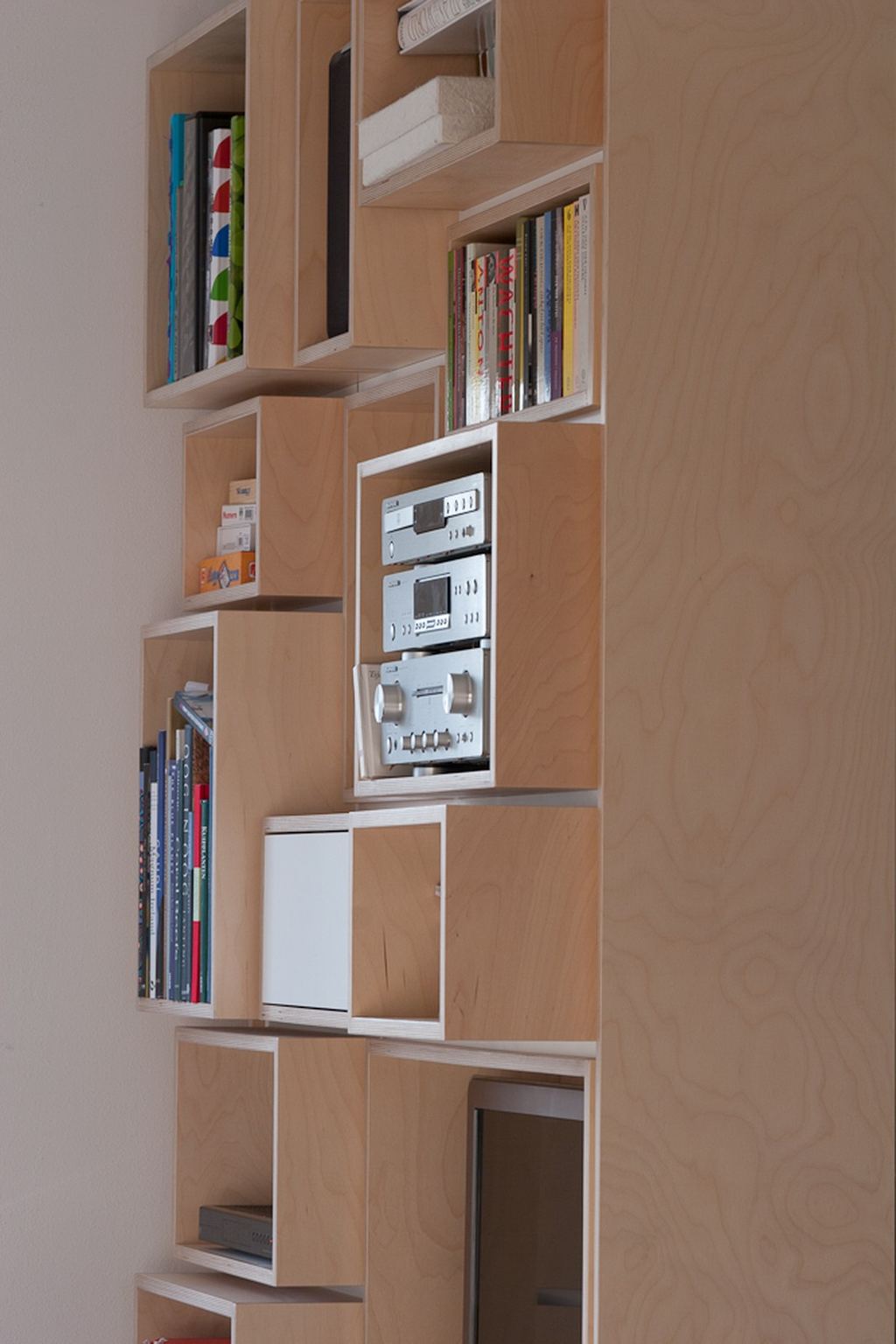 Bergkast met een stereo-installatie en boeken in de losse vakken, schuin gefotografeerd.