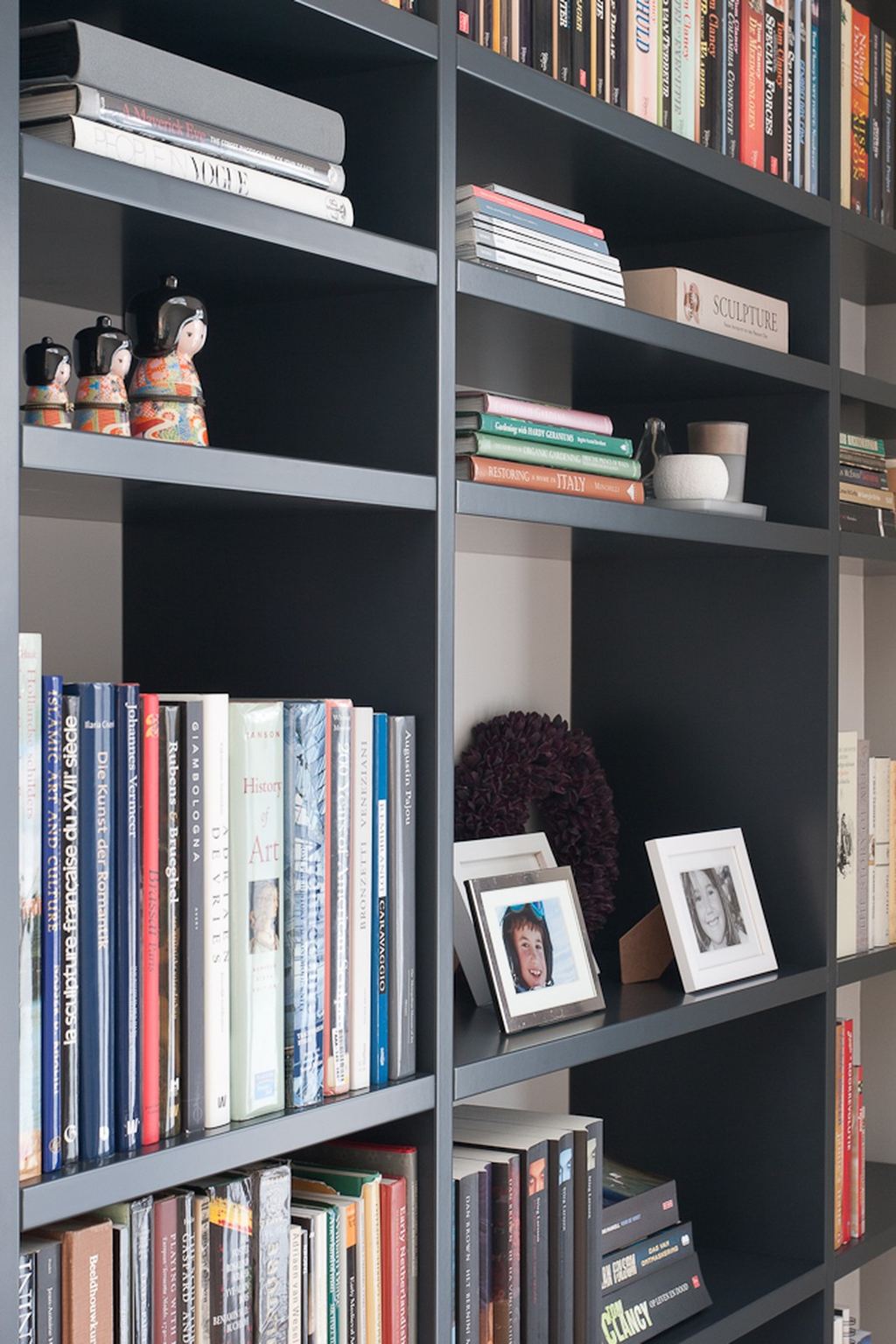 Detail van de zwarte boekenkast met een open, gelaagd vakkenpatroon.