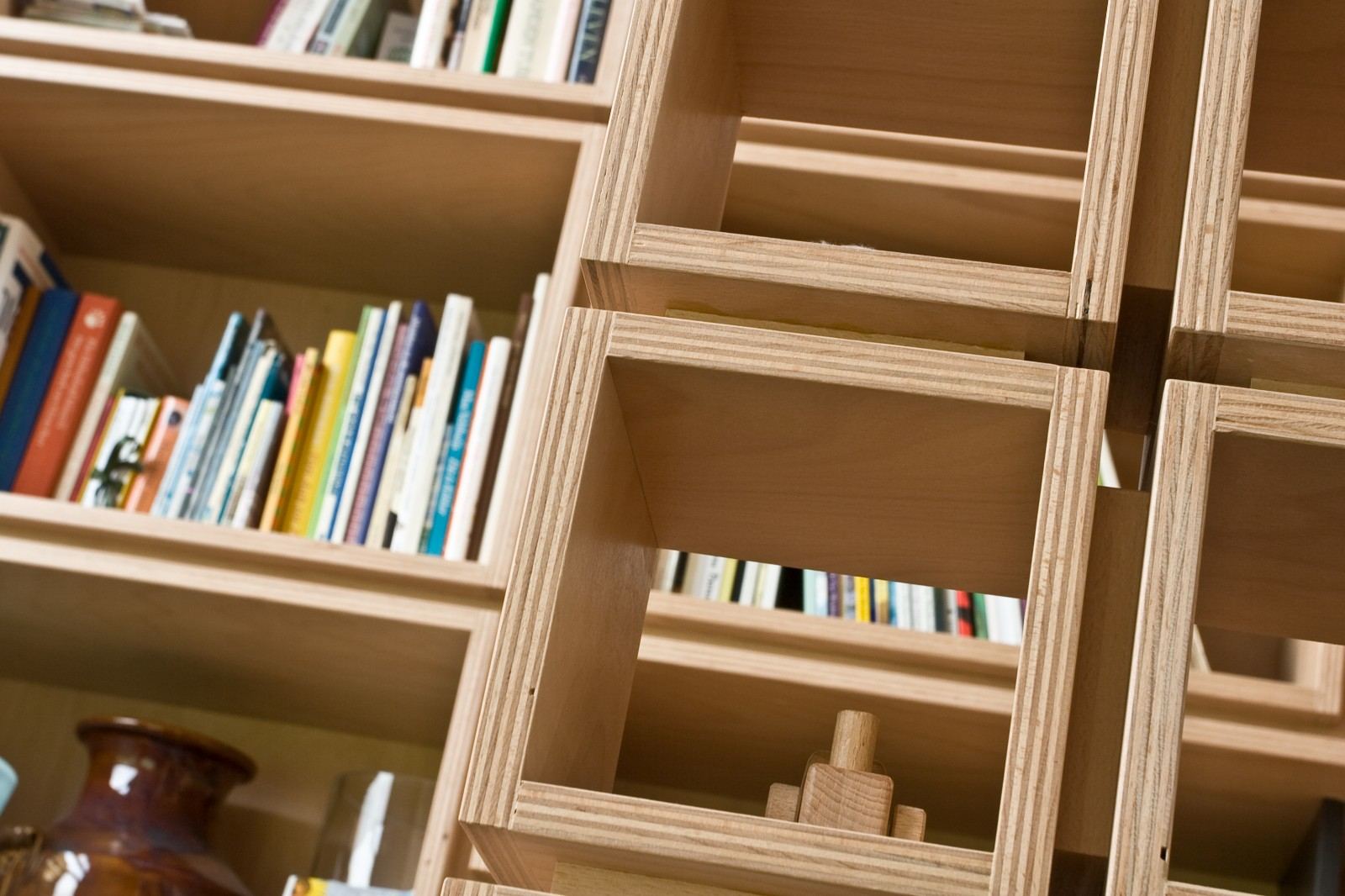Traptrede tussen vakken met boeken en een aardewerken vaas.