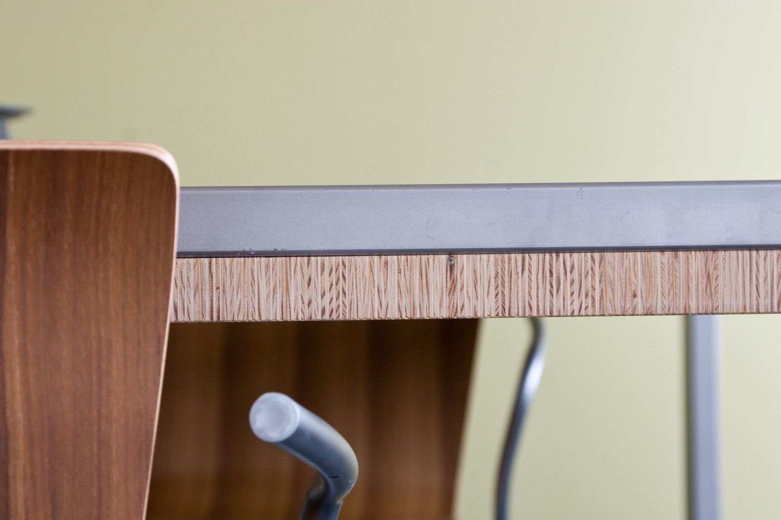 Detail van de plexwood rand van de tafel op het stalen onderstel.