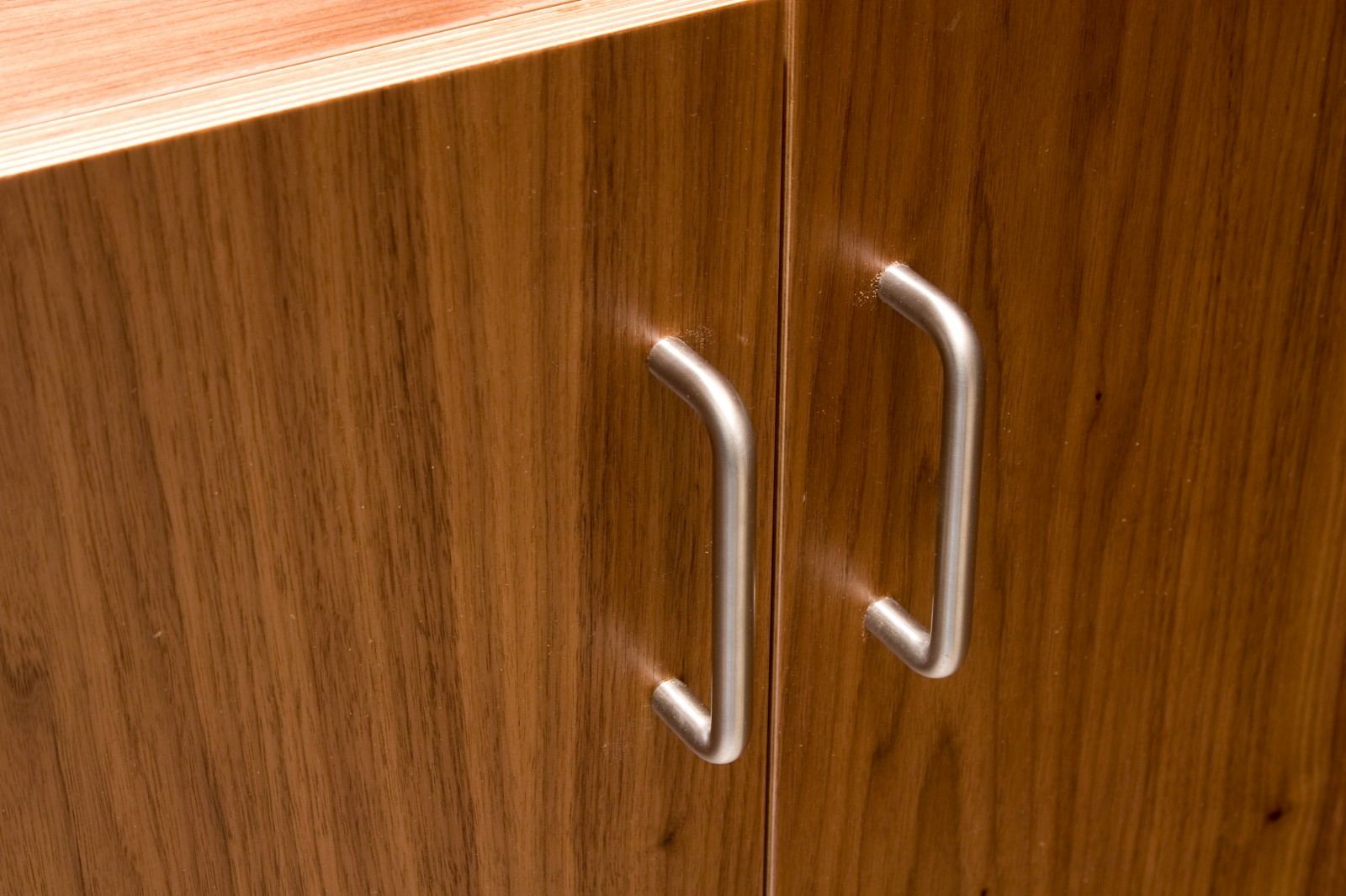 Close-up van de houtnerf en metalen grepen van de kastdeuren.
