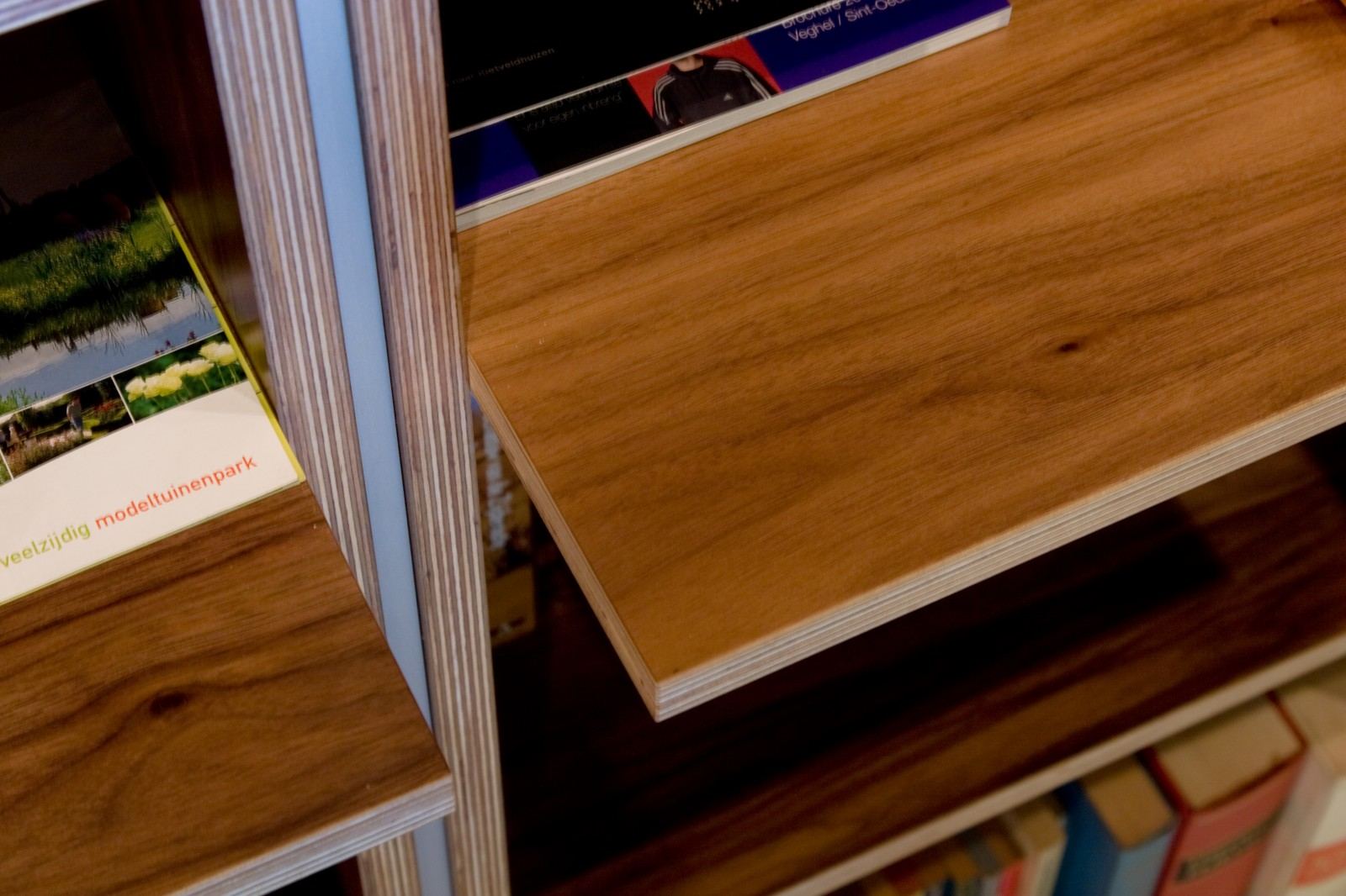 Detail van een smal, uitstekend tijdschriftenvak in de boekenkast.