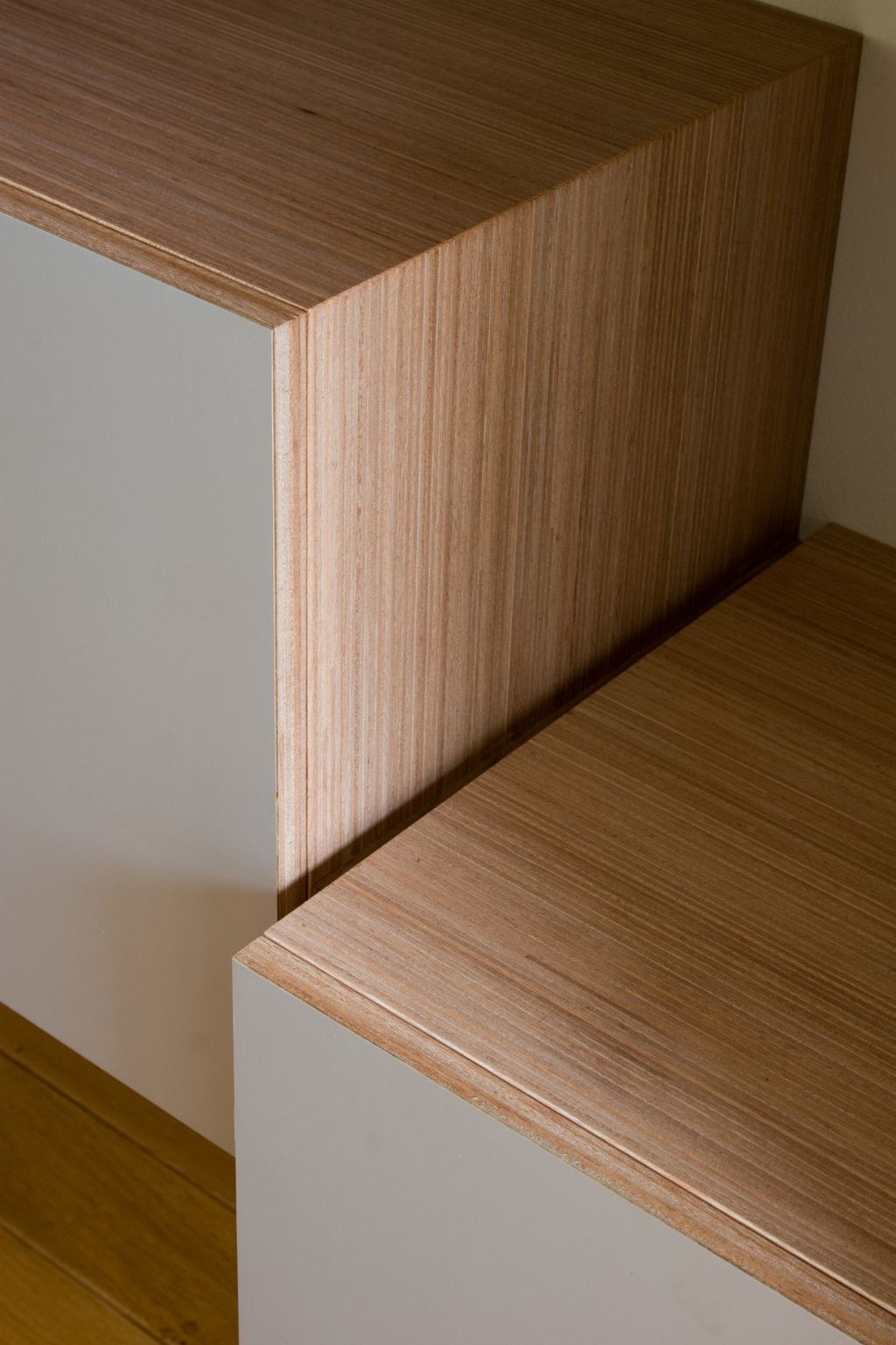 Detail van de hoek waar een lichte houten kast een wit front raakt.
