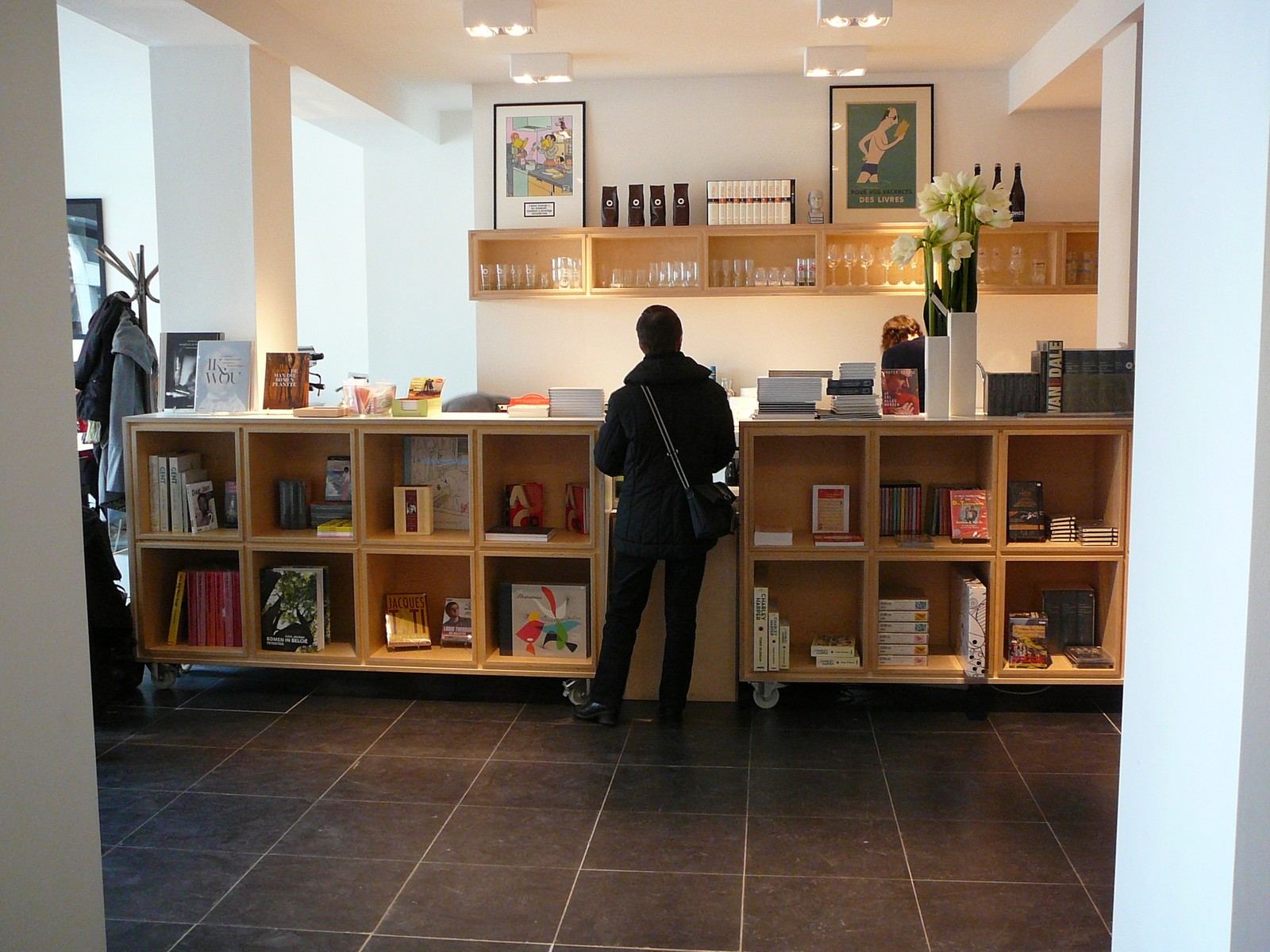 Verrijdbaar boekenrek van licht hout op wieltjes, naast een balie.