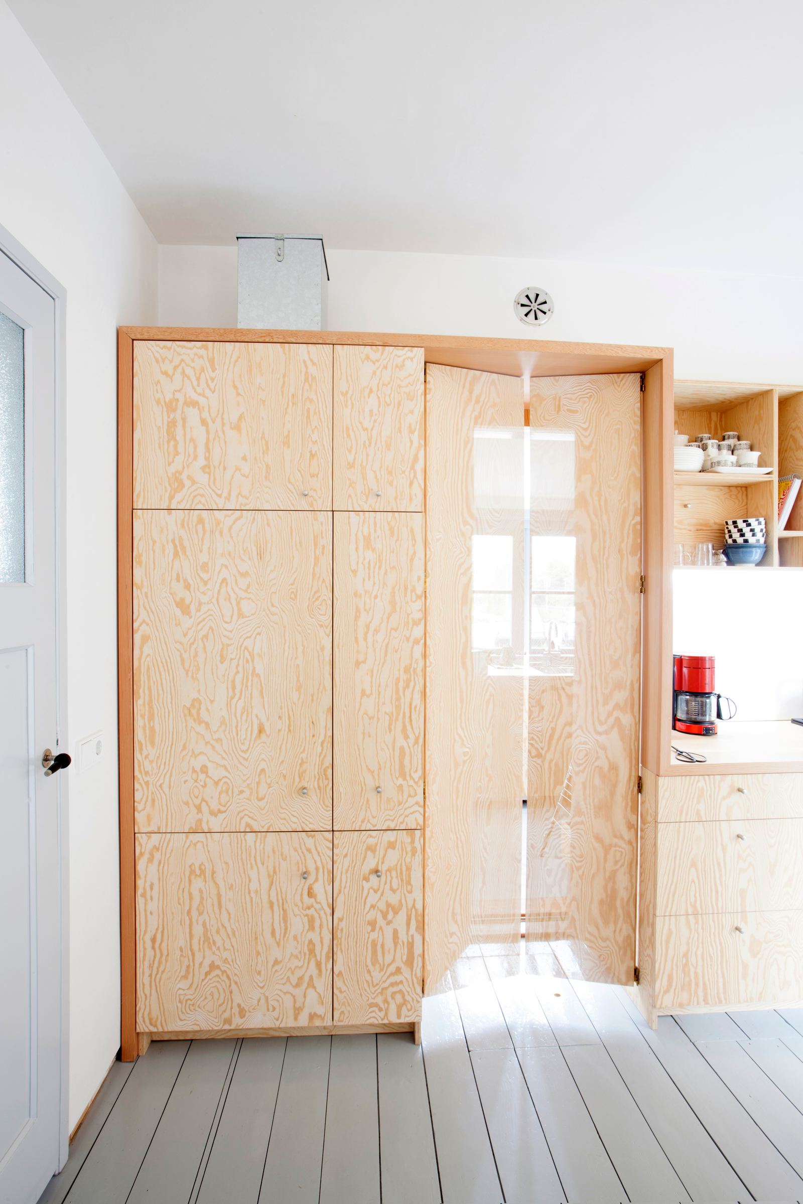 Houten keukenkast met een openstaande vouwdeur, gezien vanuit een andere hoek.