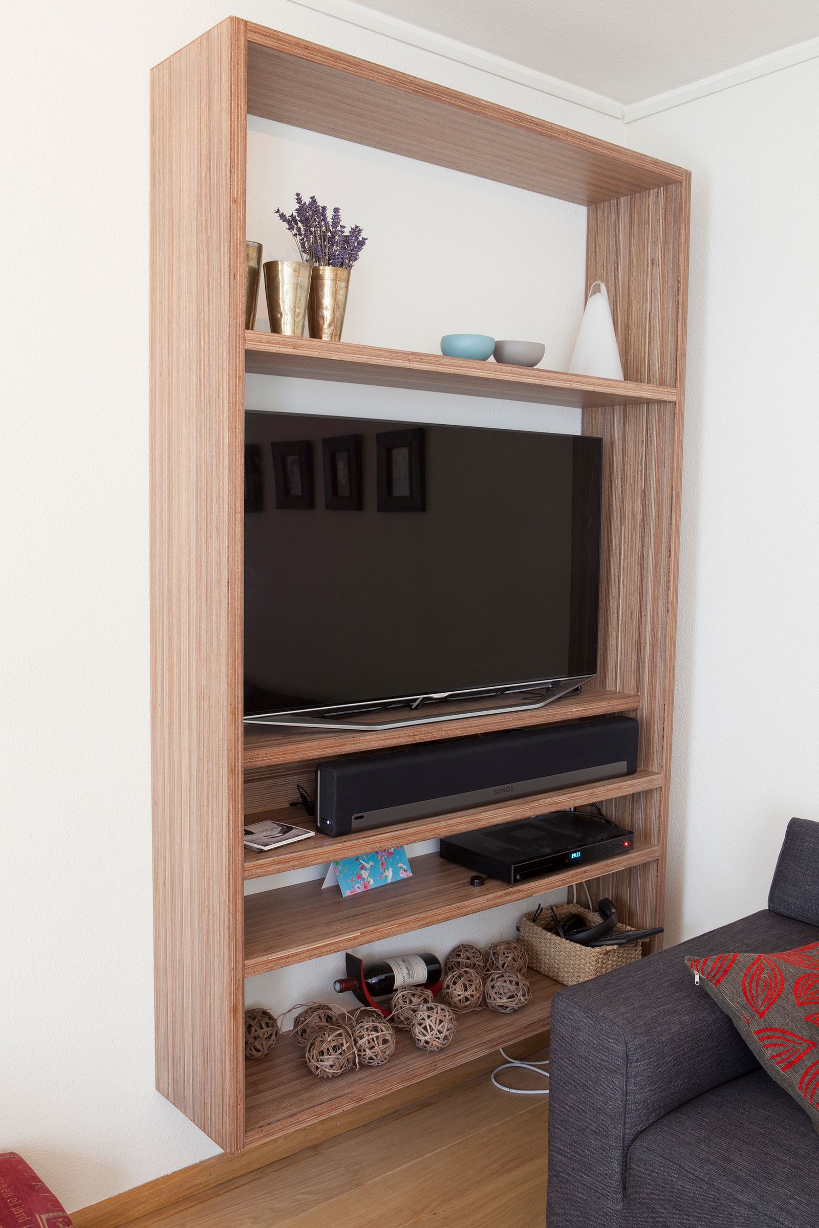 Televisiekast in plexwood met open vakken boven en onder de tv.