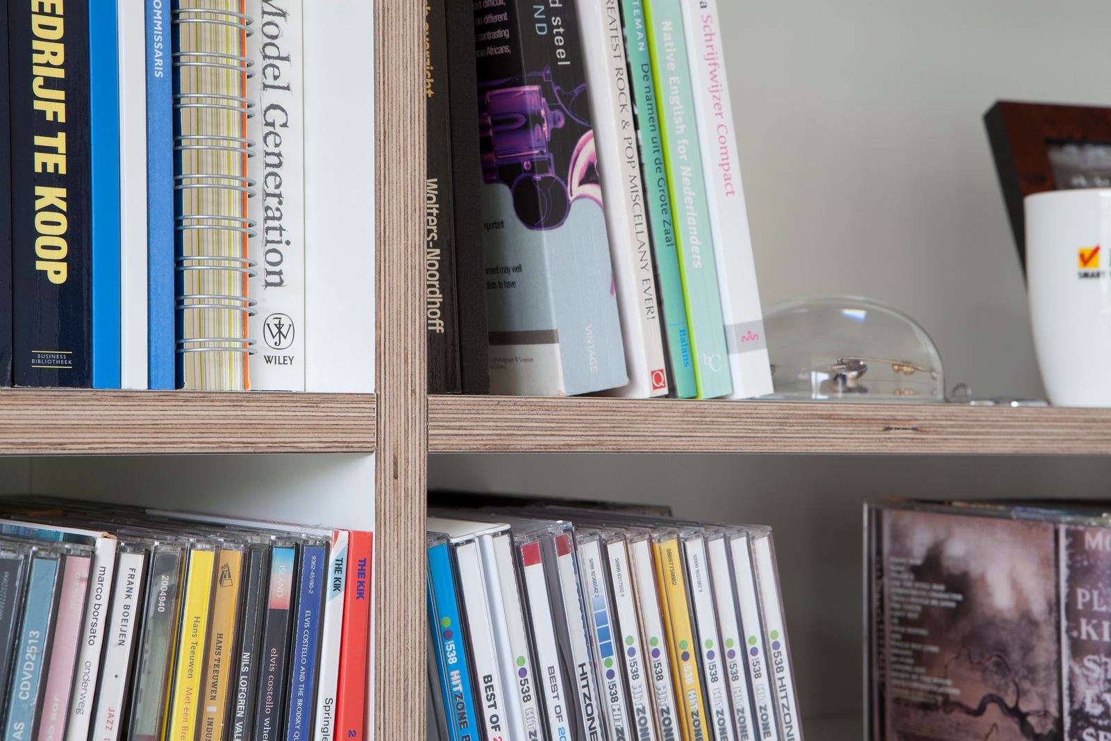Detail van boeken en cd's op de open planken van de kast.