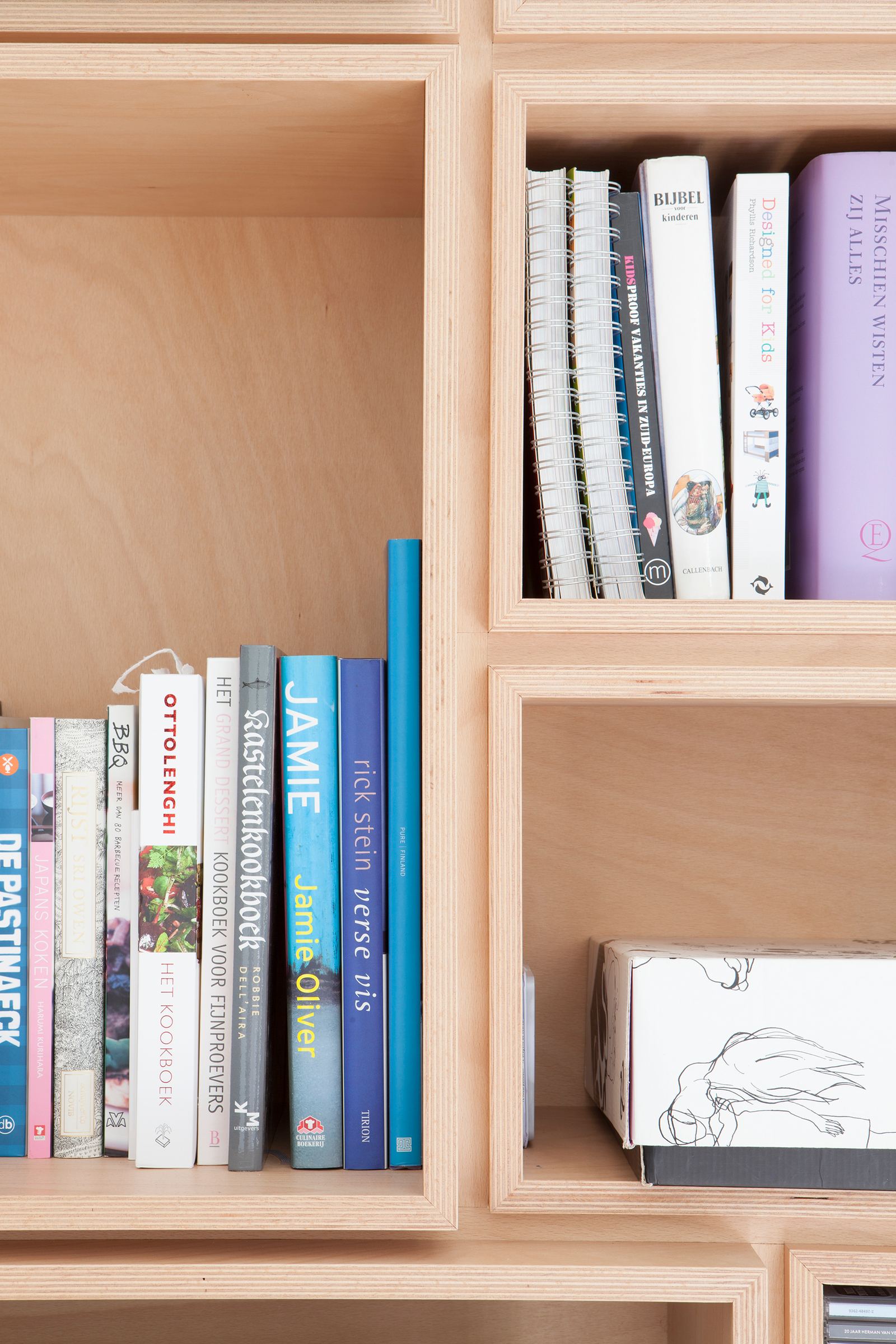 Detail van twee kastvakken met kookboeken en kinderboeken.